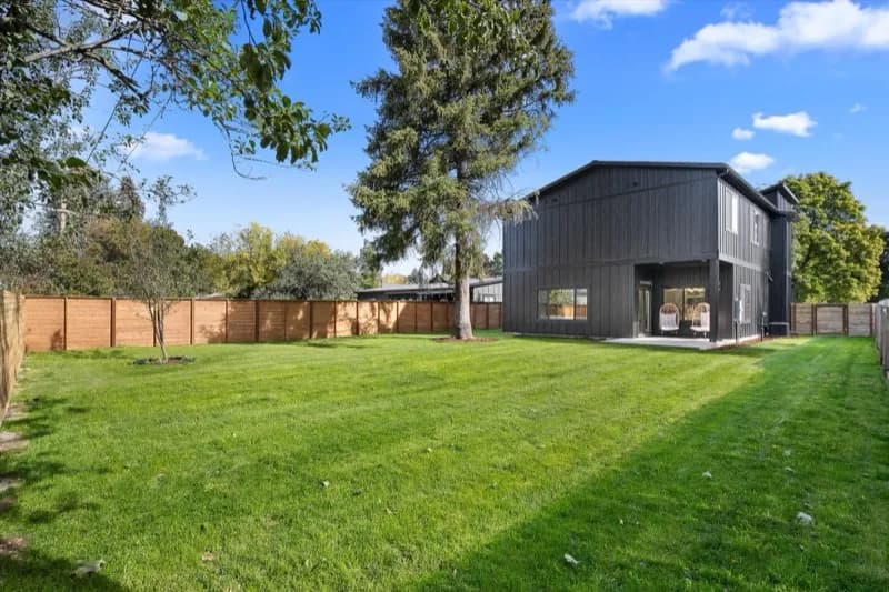 Contemporary home backyard with dark siding and large yard